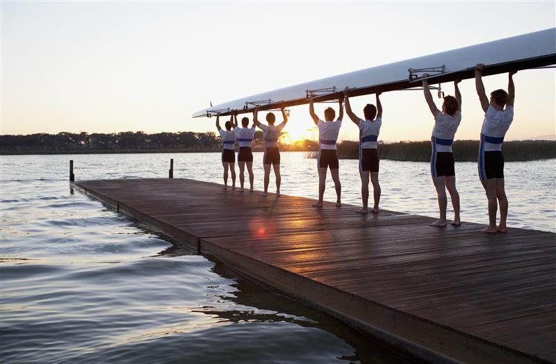 Équipage d'aviron portant son bateau, parfaitement aligné